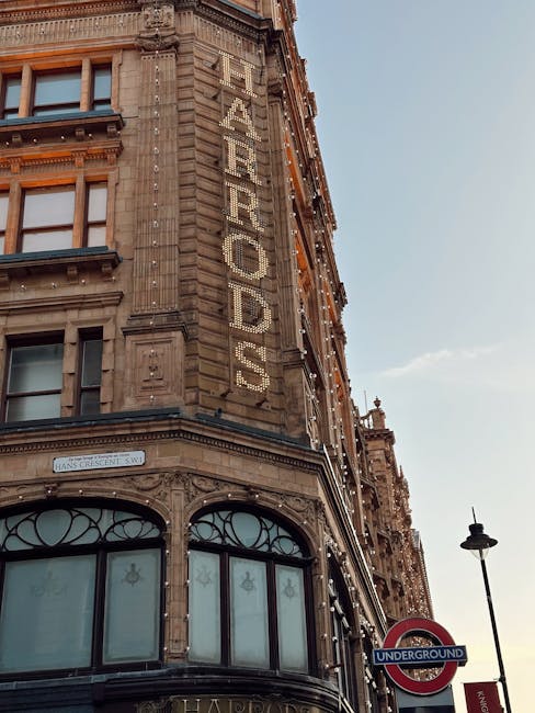 A close-up view of the corner of a historic multi-story building in Mayfair, featuring ornate stonework and large arched windows on the ground floor. The building's facade is decorated with intricate 